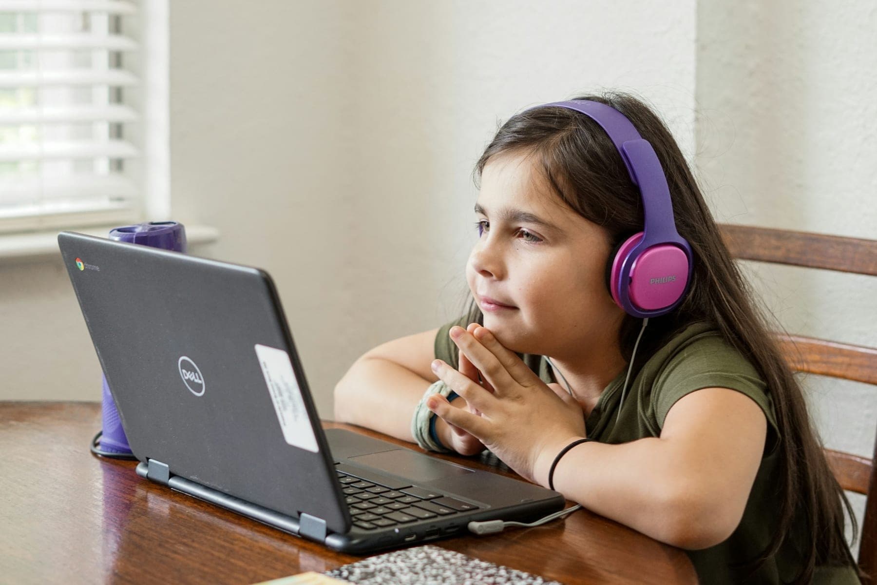Uma menina com auscultadores a assistir a uma aula no computador portátil