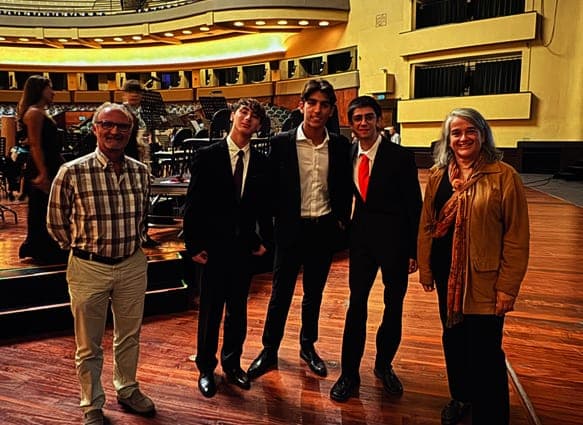 Três jovens músicos de fato com dois adultos, no palco do Coliseu do Porto depois de um concerto