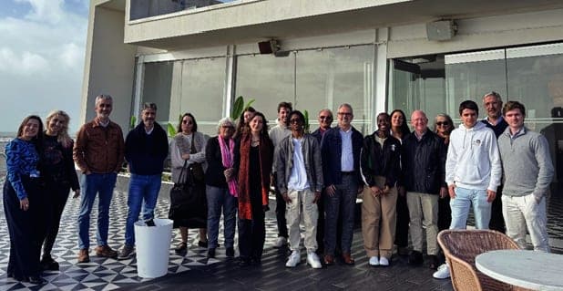 Grupo de cerca de vinte pessoas de pé num terraço, com o céu e o mar ao fundo