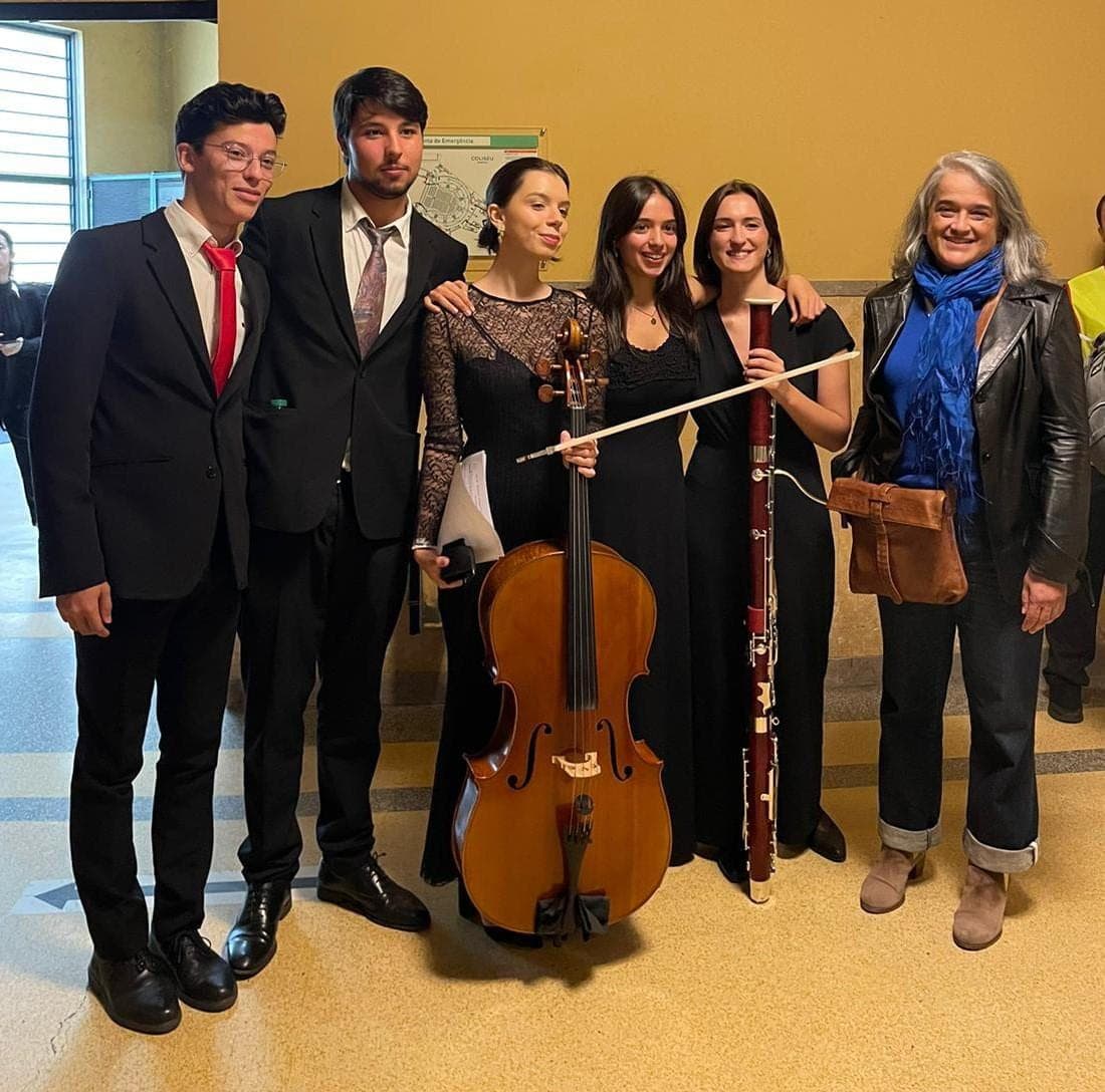 Cinco jovens músicos de fato, com um violoncelo e um fagote, ao lado de uma mulher de cabelo grisalho e lenço azul, no Coliseu do Porto