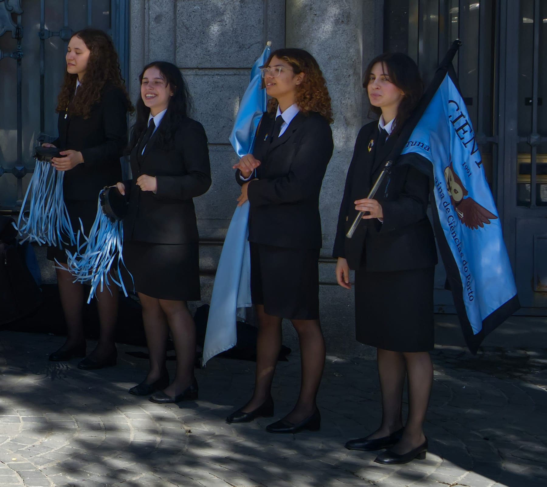 Estudantes de traje académico, com capas e uma bandeira