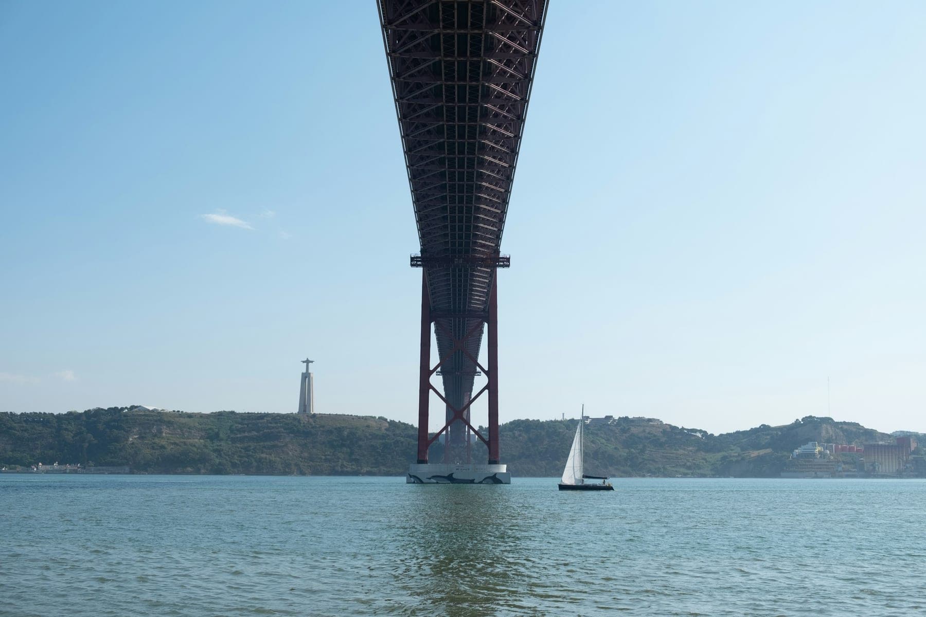 Um veleiro no Tejo a passar junto à Ponte 25 de Abril, com o Cristo Rei ao fundo